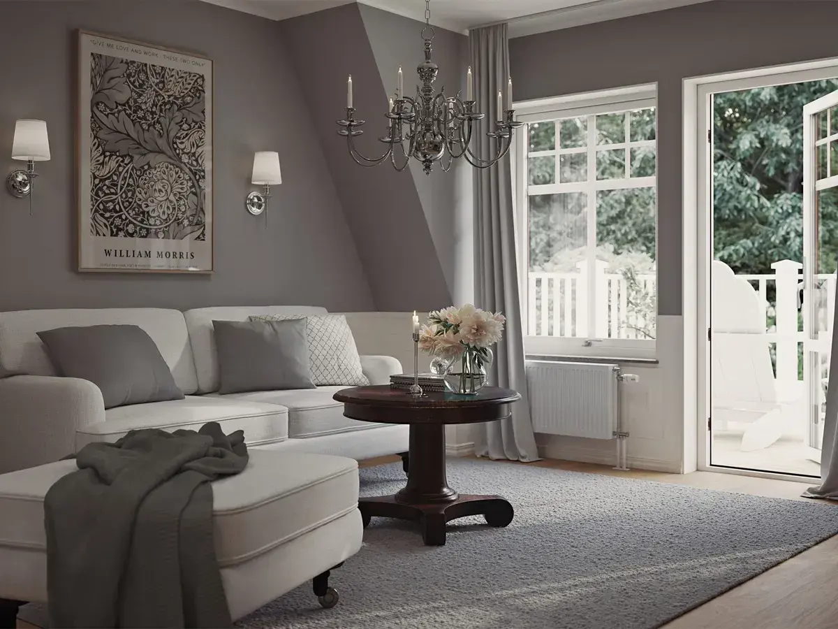 En ljus och luftig salong med sekelskifte inredning. En vit soffa med kuddar, ett runt träbord med blommor och en öppen balkongdörr.