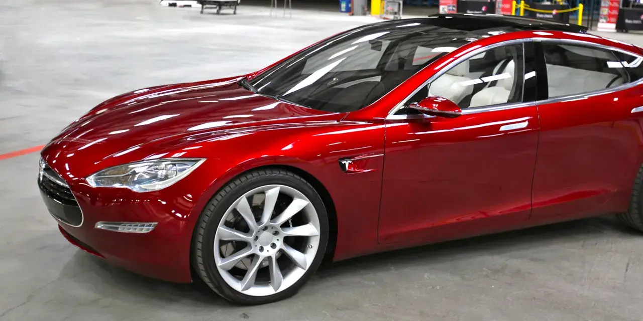 Czerwony Tesla, który mąż nie chce dać mi samochodu, lśni w słońcu.