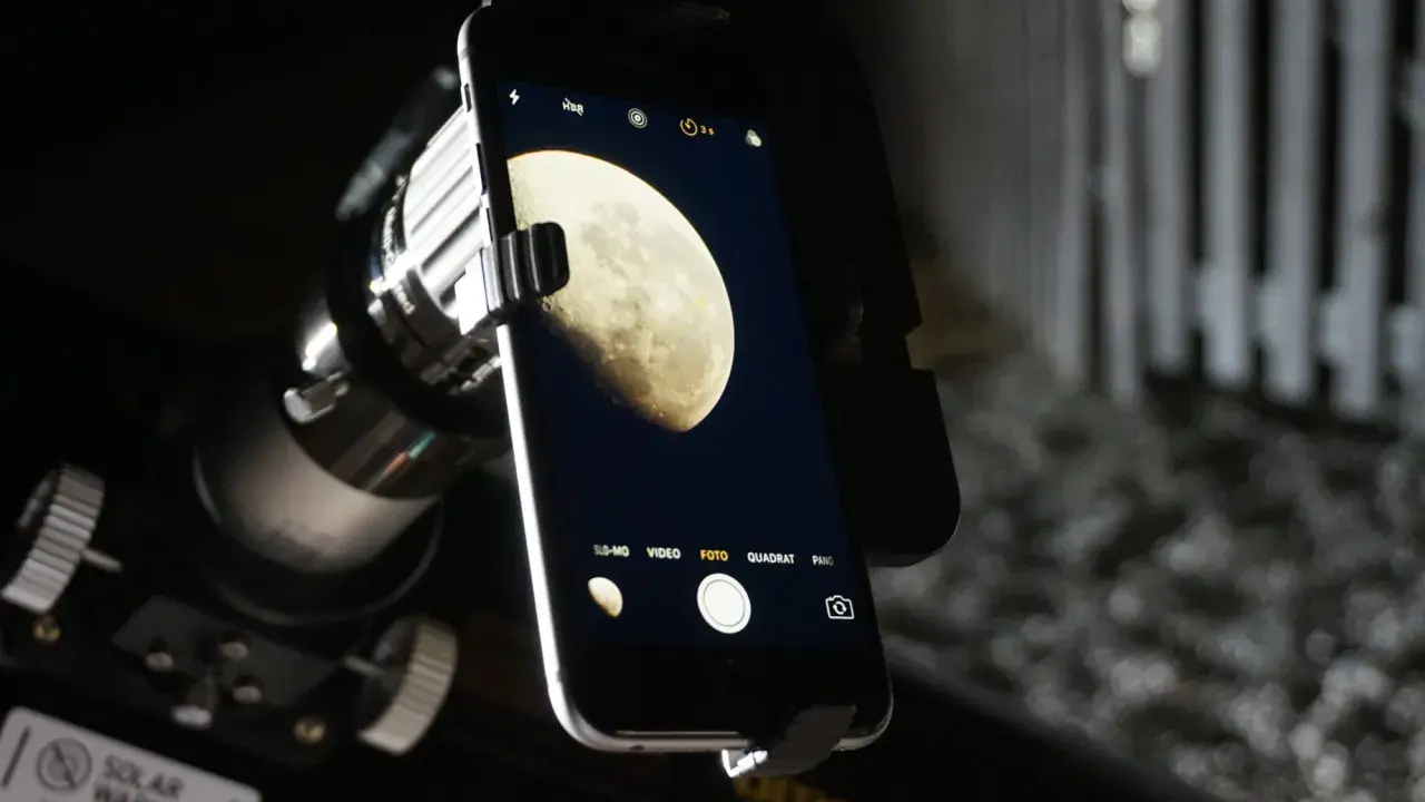 Telefon z aparatem uchwycił zdjęcie księżyca w pełni, widocznego przez teleskop.