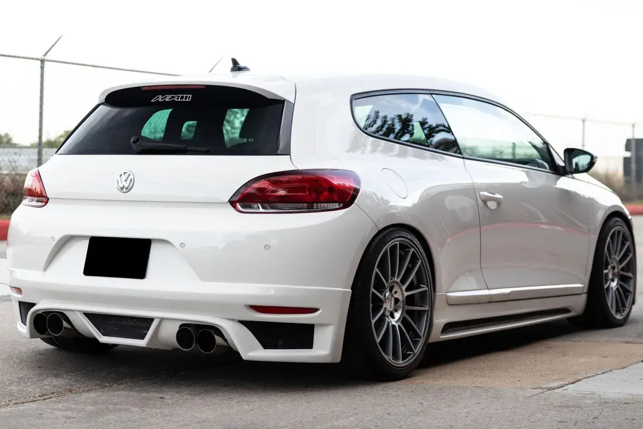 La parte posteriore di una Volkswagen Scirocco bianca, con un diffusore sportivo e quattro scarichi.