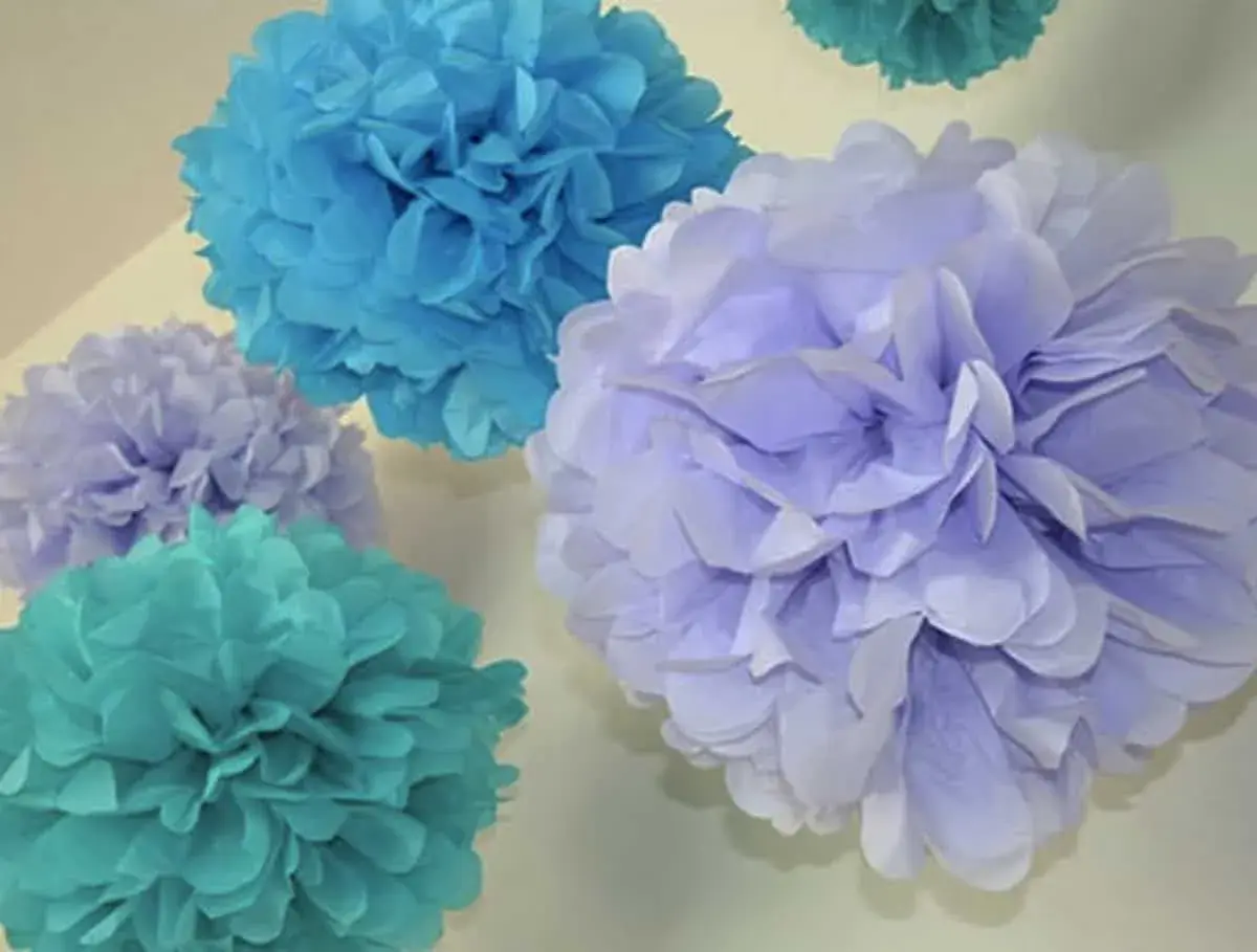 Pompones de papel pinocho en tonos azules y lilas, perfectos para manualidades decorativas.