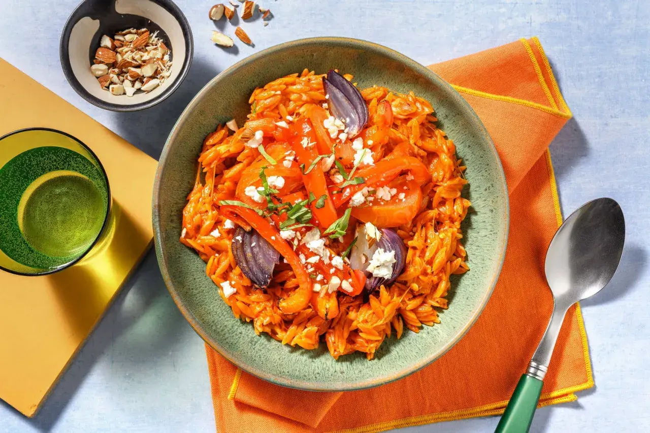 En skål med orzopasta med rostade grönsaker, fetaost och mandlar. Ett perfekt basilika recept för en snabb middag.