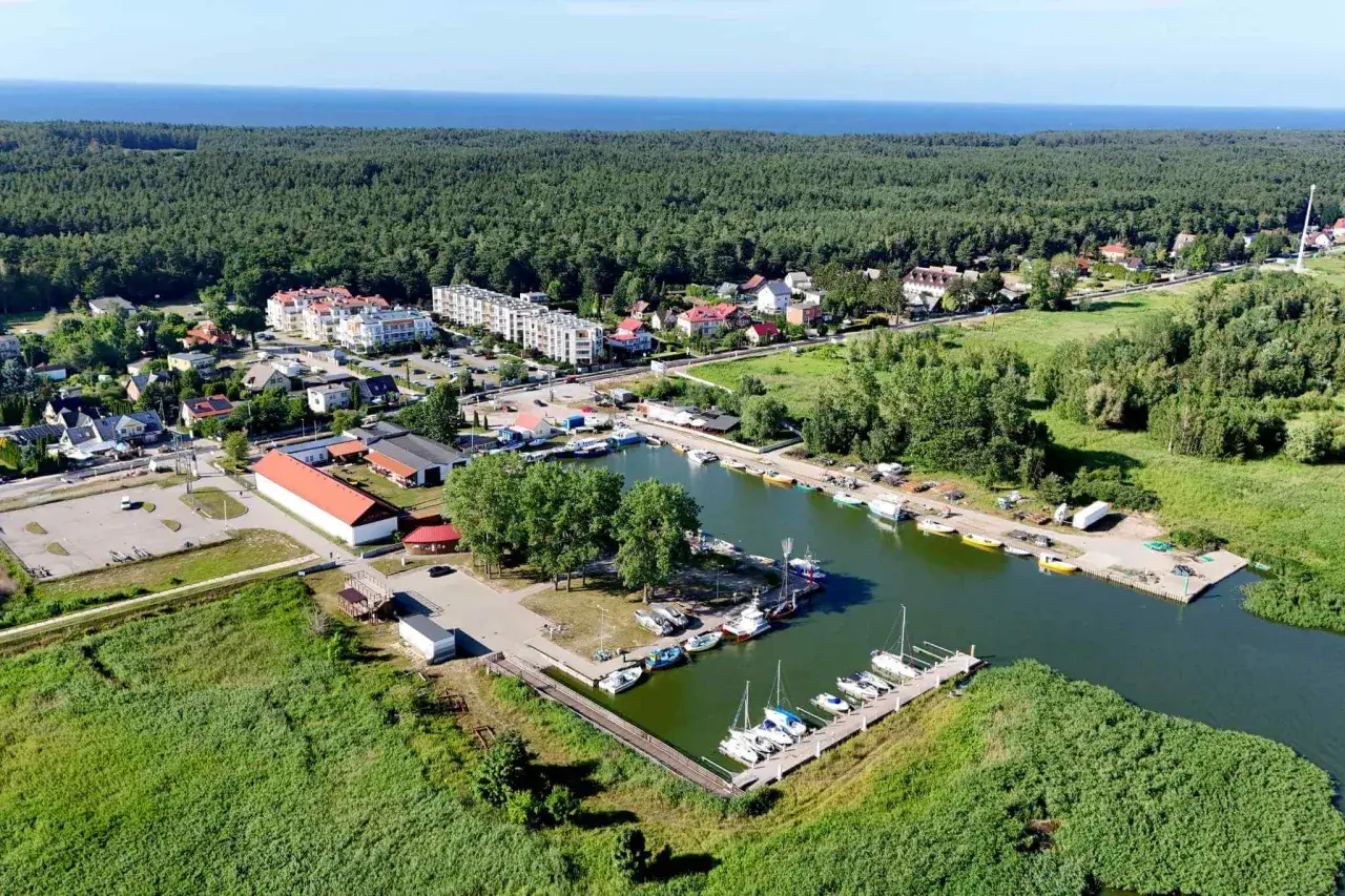 Widok na przystań jachtową i zabudowania w otoczeniu zieleni, idealne miejsce na camping Mierzeja Wiślana.