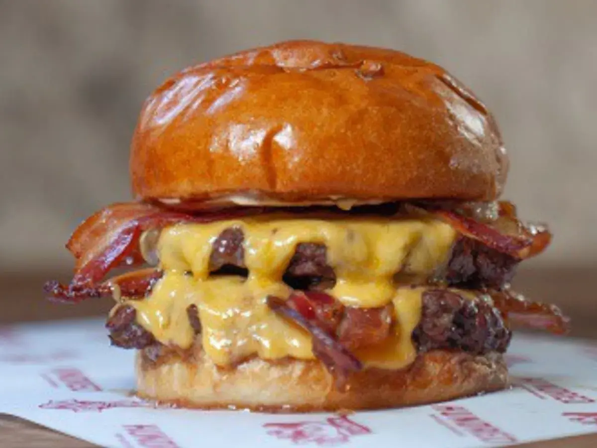 Jugosa hamburguesa doble con queso fundido y crujiente bacon, un festín que vale hundred Valencia.