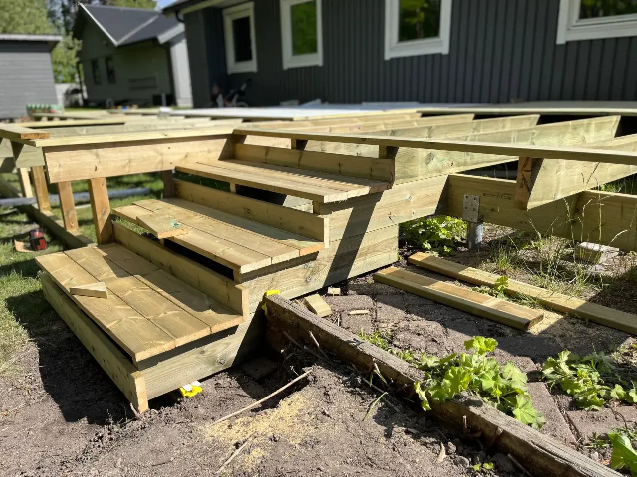 Nybyggd veranda i trä med trappsteg, redo att färdigställas.