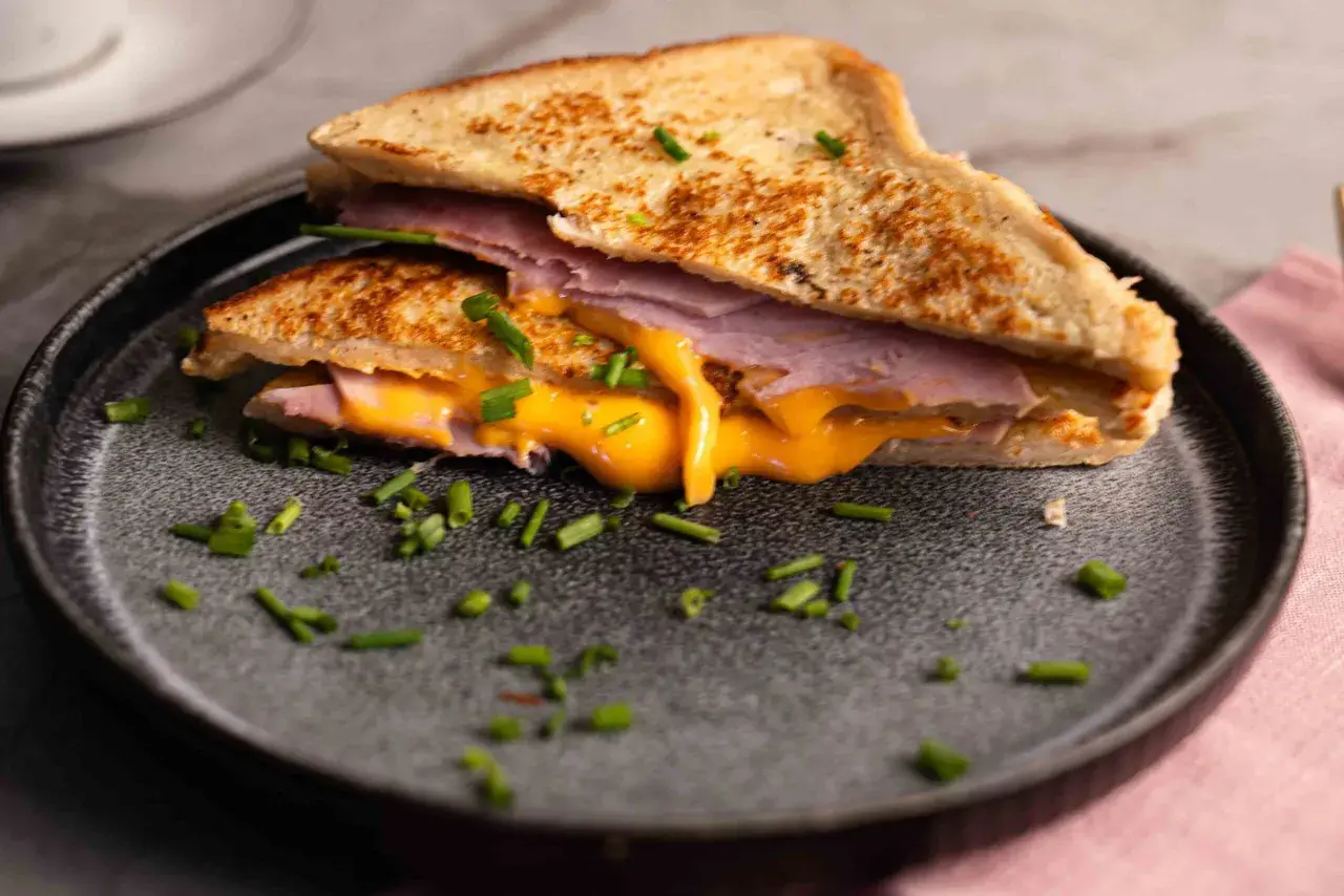 Herzhaftes French Toast mit Schinken und geschmolzenem Käse, garniert mit Schnittlauch.