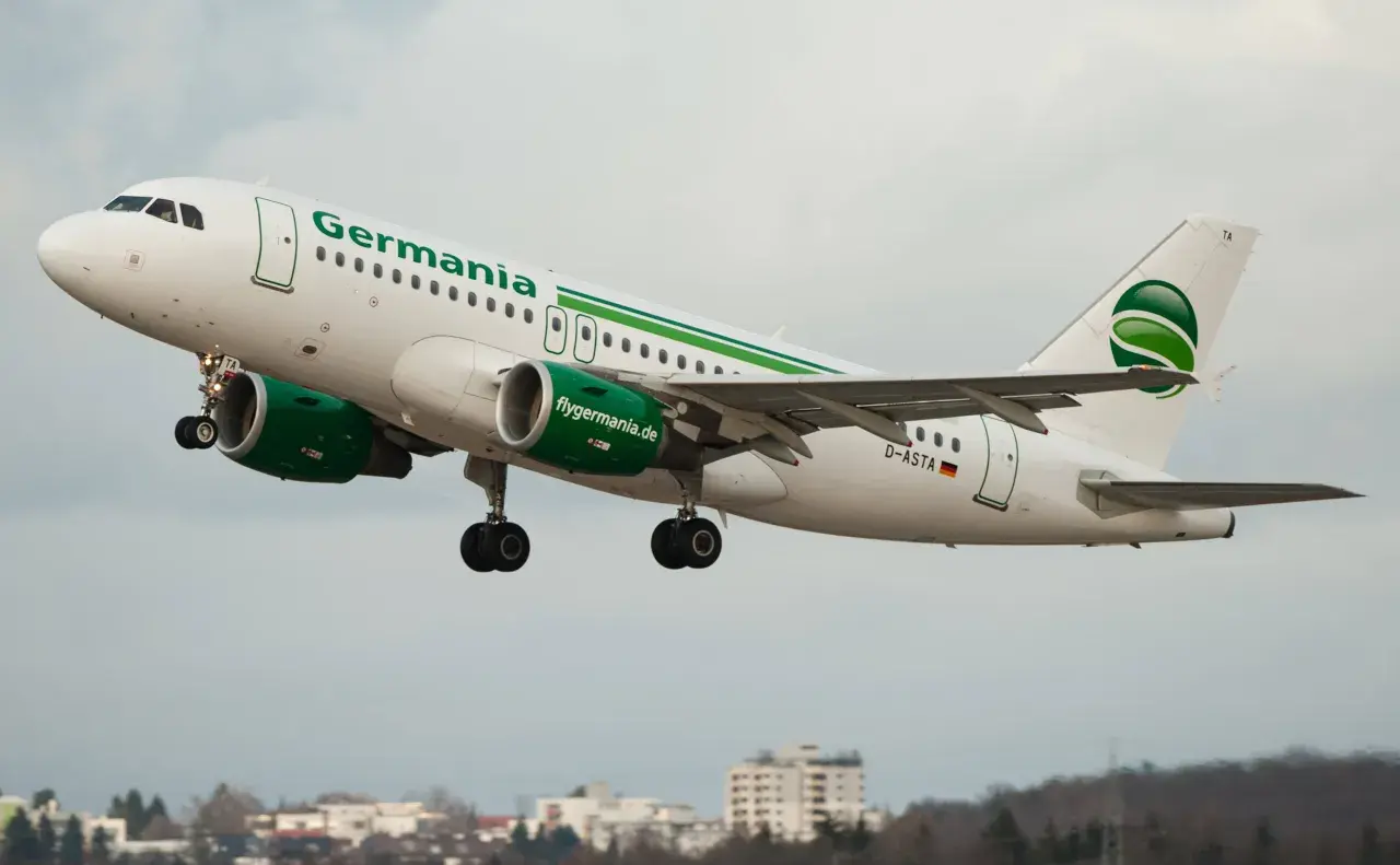 Samolot linii lotniczych Germania z zielonym logo startuje na tle pochmurnego nieba.