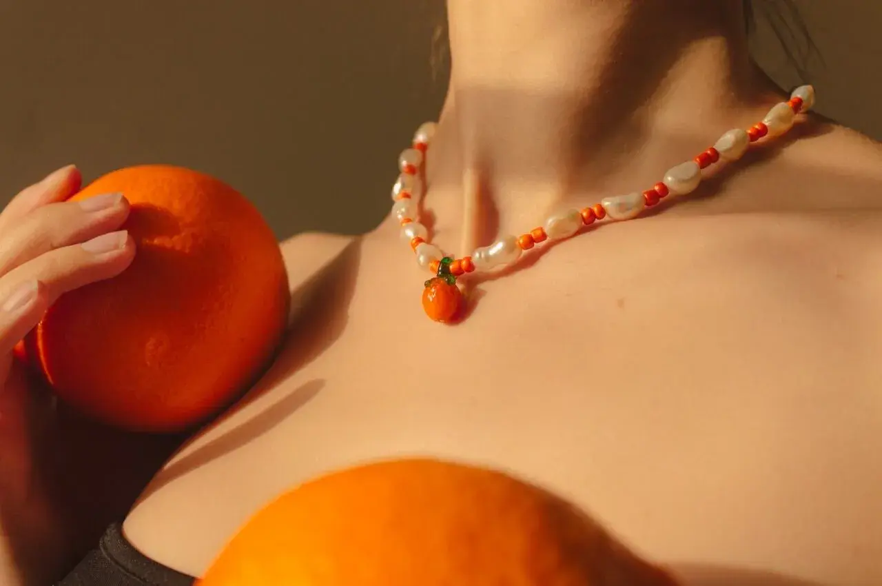 Collar de perlas y cuentas naranjas con un colgante de mandarina, como si fuera un sueño con naranjas.