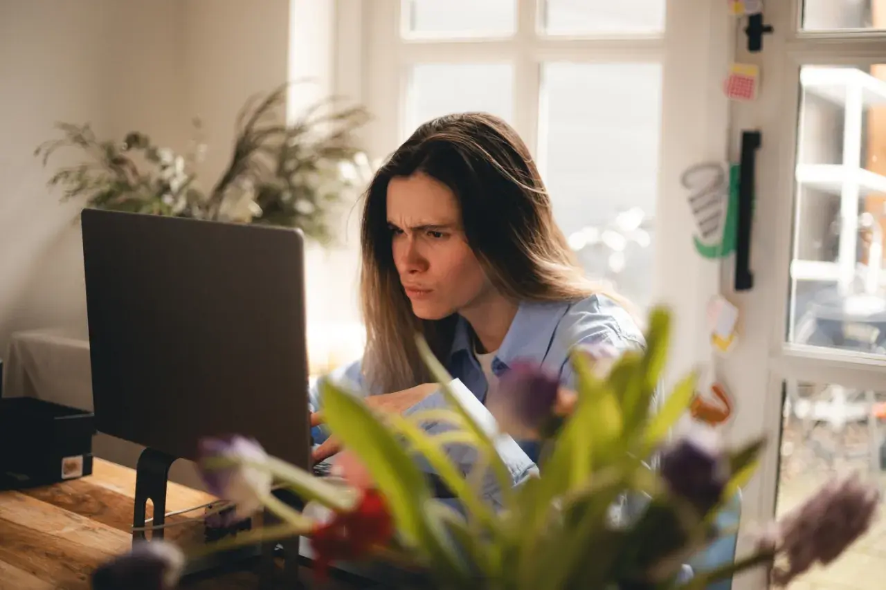 Zmarszczona kobieta przy laptopie, sfrustrowana z powodu braku połączenia z internetem.