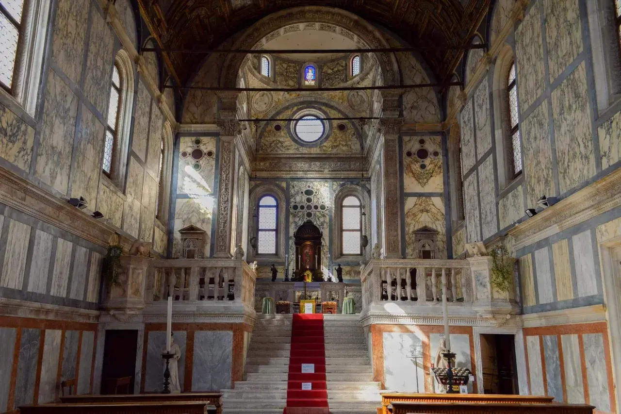 Intérieur de l'église Santa Maria dei Miracoli à Venise, avec son escalier rouge menant à l'autel, le tout orné de marbre.