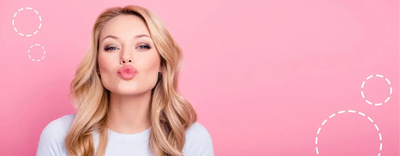 Blondynka z okrągłą twarzą i falowanymi włosami posyła całusa.