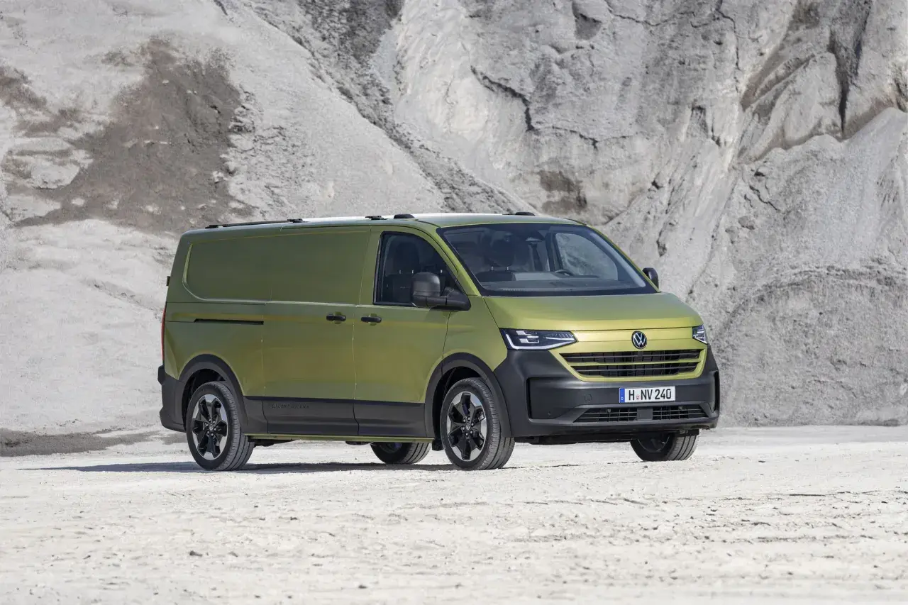 Un furgone Volkswagen Transporter color verde oliva, con un design moderno e robusto, pronto per ogni avventura. Le sue dimensioni sono perfette per il trasporto.