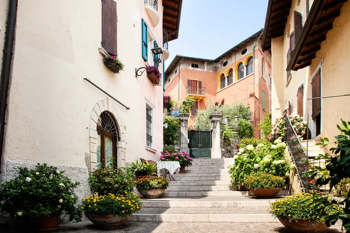 Un vicolo fiorito nel gardone riviera centro storico, con scale di pietra, case colorate e piante rigogliose.