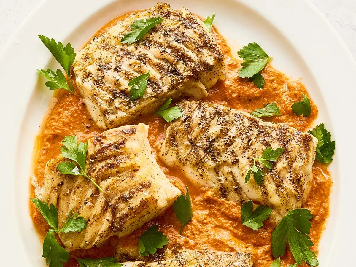 Filetes de bacalao a la parrilla con salsa de pimientos rojos y perejil fresco. Un plato principal perfecto para tus recetas de bacalao.