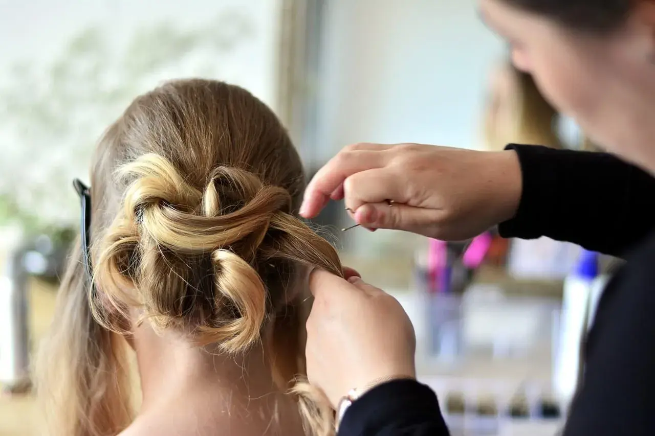 Fryzjerka tworzy elegancką fryzurę ślubną. Jej praca to sztuka, a kod zawodu fryzjer to opis jej talentu.