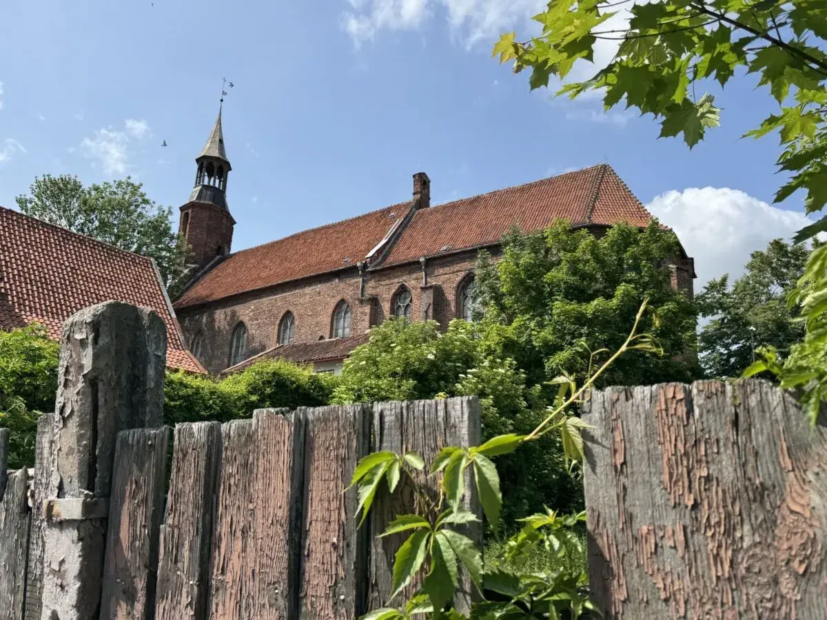Stary, drewniany płot i ceglany kościół z wieżą w malowniczym mieście na Kociewiu.