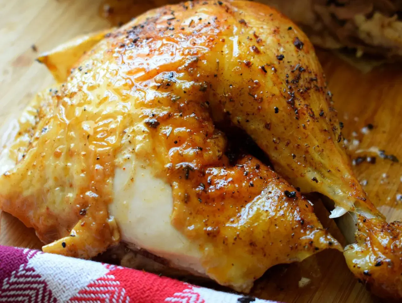 Un délicieux demi poulet BBQ, la peau dorée et brillante, prêt à être dégusté.