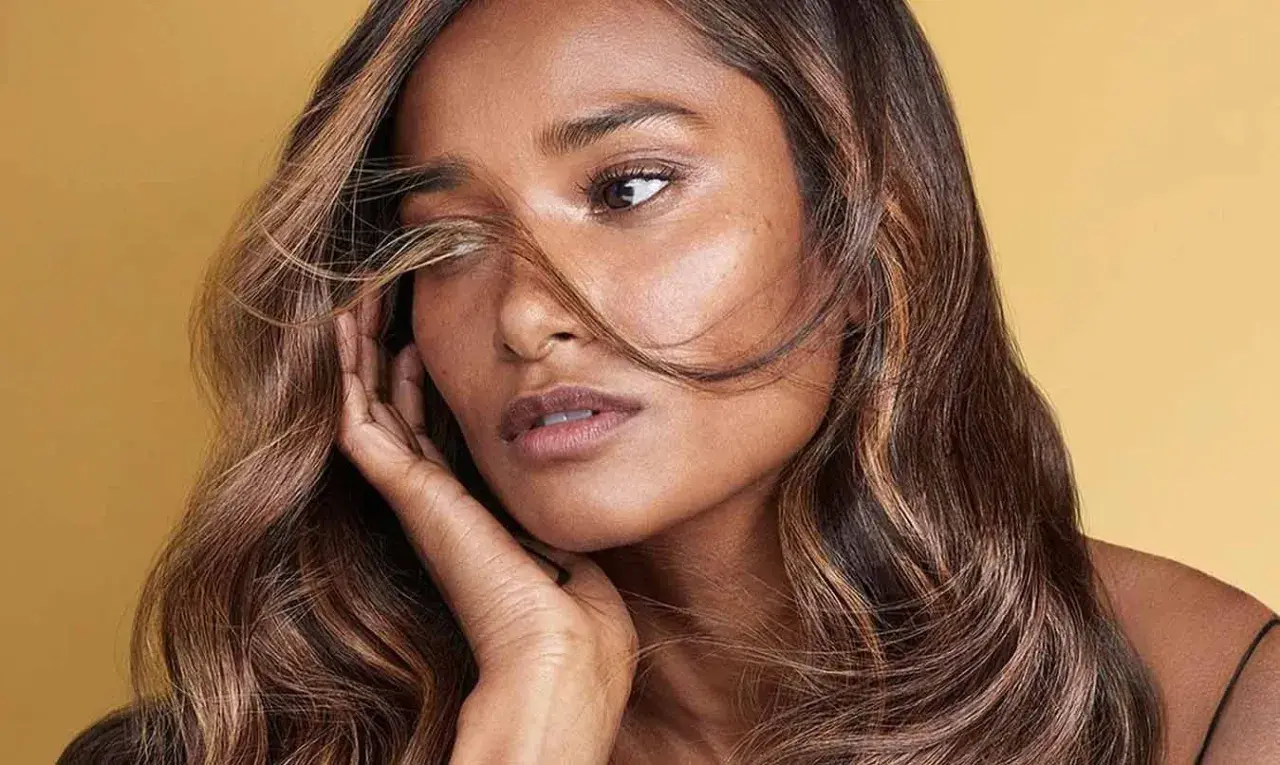 Morena con cabello castaño y reflejos caramelo, un estilo que ilumina su rostro.