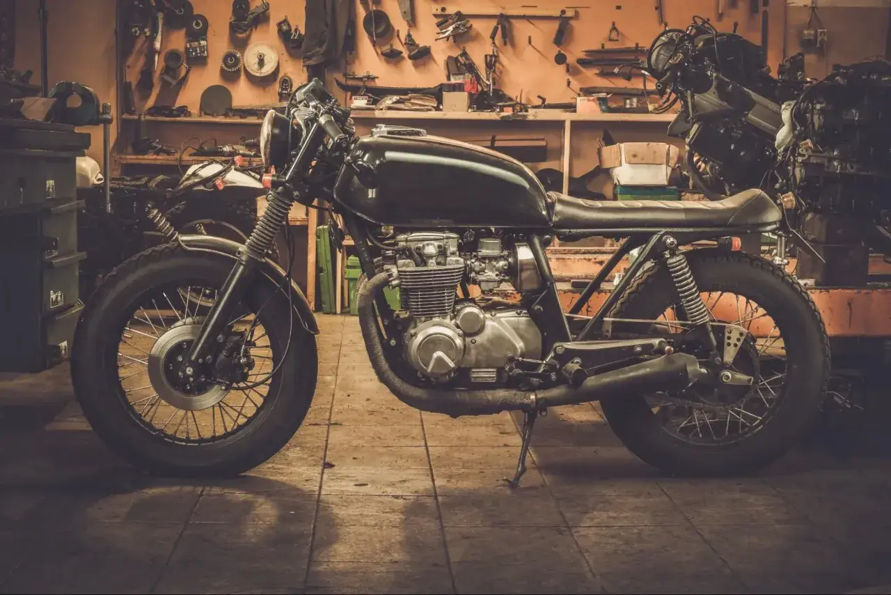 Czarny motocykl typu cafe racer w warsztacie, gotowy do sezonu.