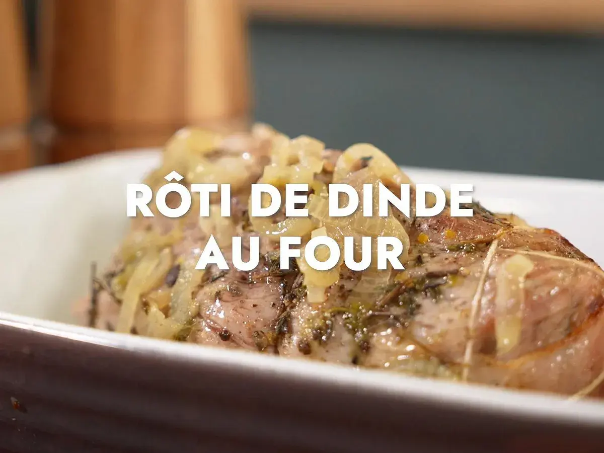Un rôti de dinde au four, savamment assaisonné d'herbes et d'oignons, cuit à la perfection dans un plat en céramique.