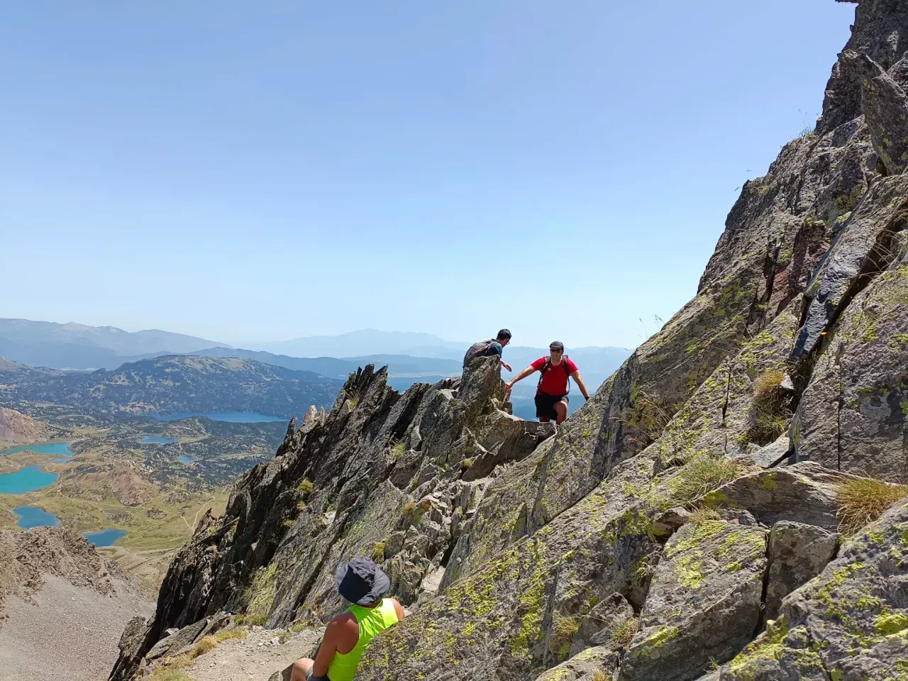Trepando por rocas, un pic carlit con lagos turquesas de fondo.