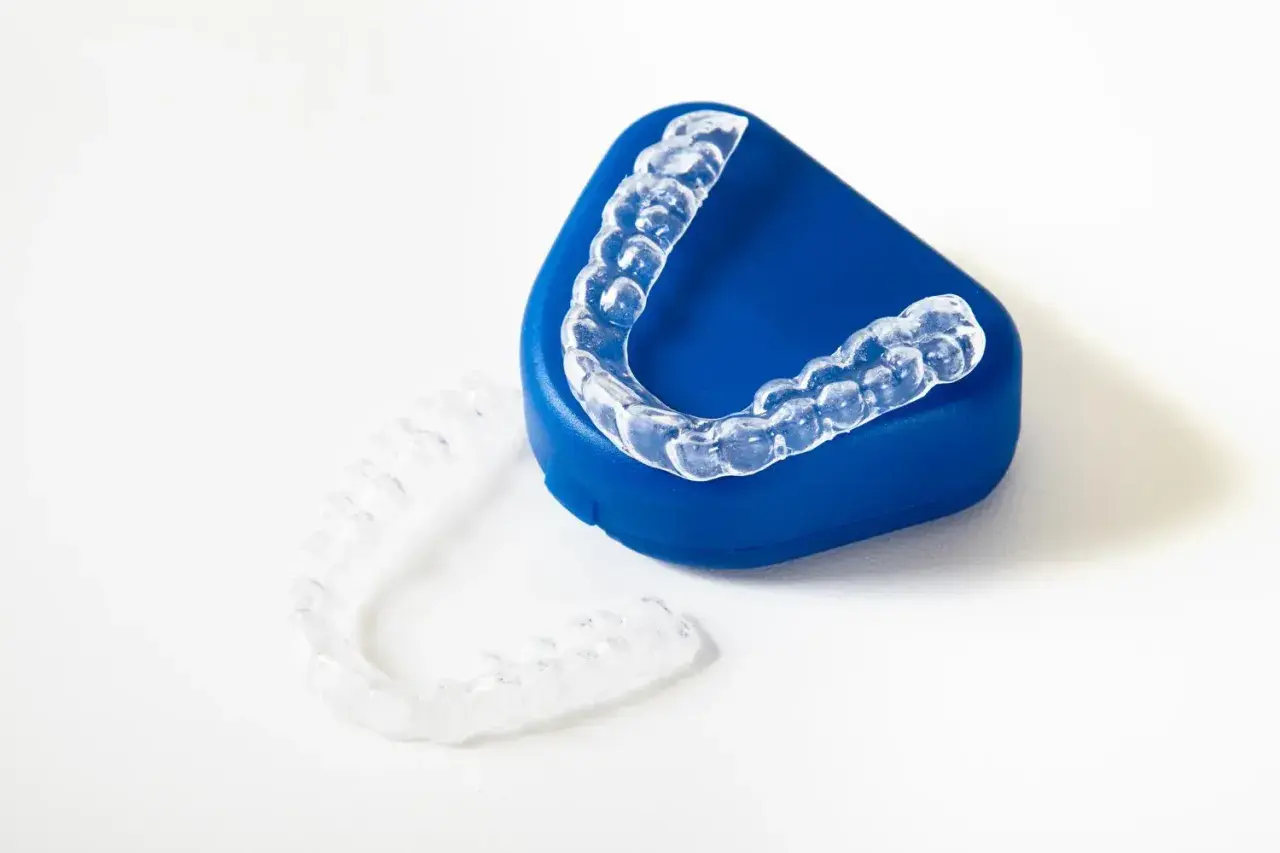 Alineadores transparentes para ortodoncia, uno sobre un estuche azul y otro al lado. ¿Cuánto cuesta el invisible line?
