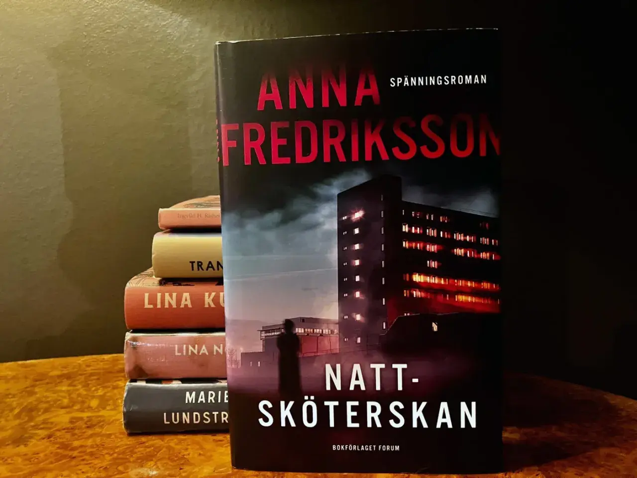 Anna Fredrikssons spänningsroman "Natt-sköterskan" står framför en stapel böcker.
