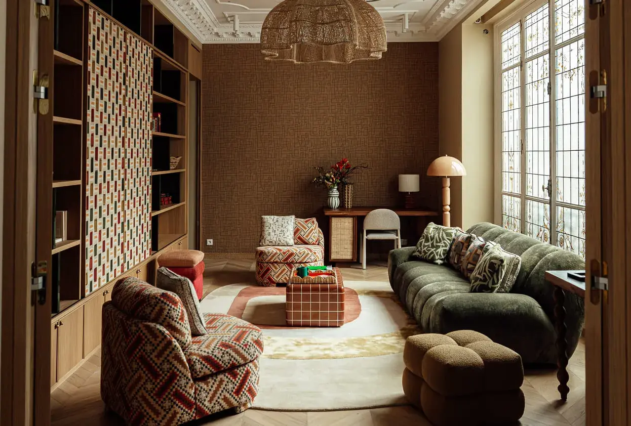 Salon cosy avec canapé vert, fauteuil à motifs, table basse cubique et étagères. L'ambiance invite à **acheter avant de vendre** ce style unique.