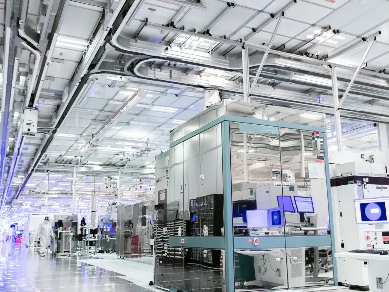 Czysty, nowoczesny zakład produkcyjny, gdzie powstają technologie dla największych firm IT na świecie. W tle widać linie produkcyjne i systemy transportowe.