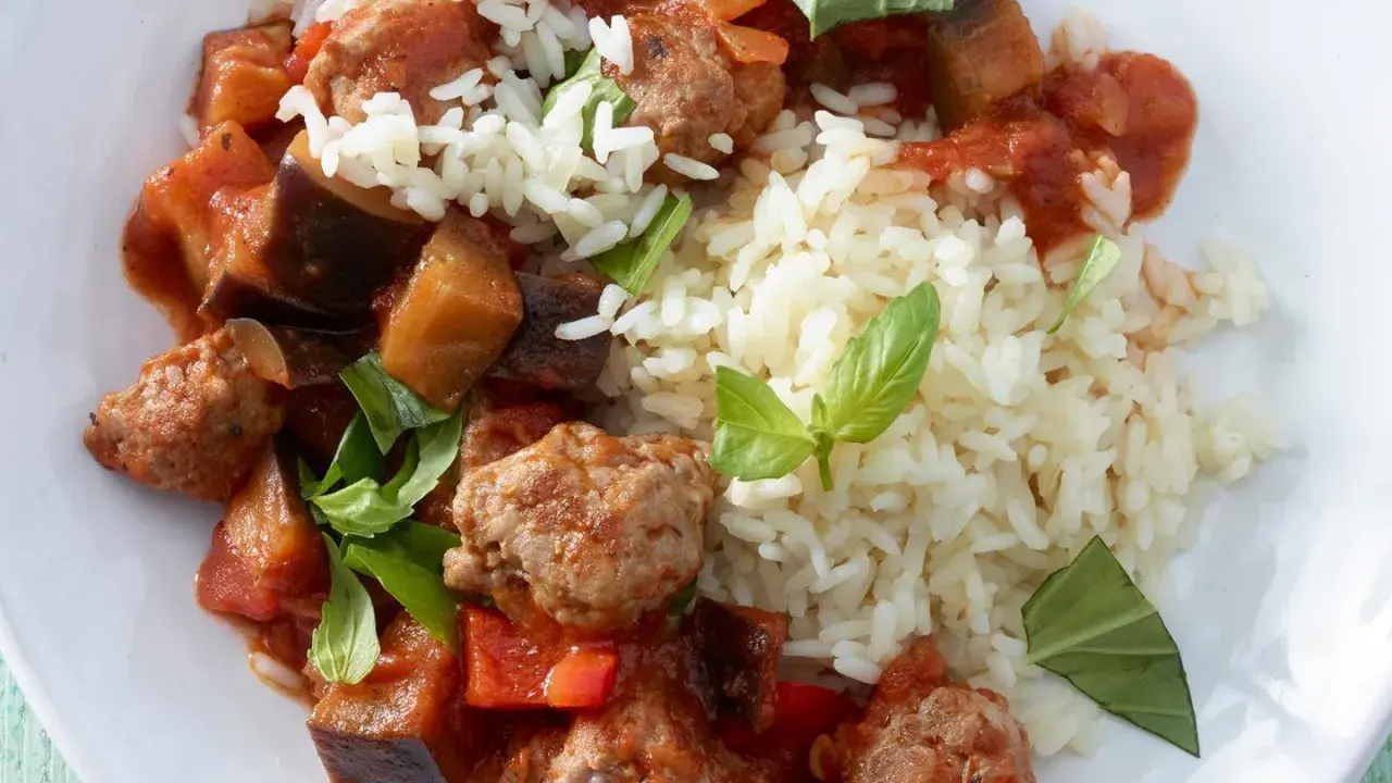 Herzhafte Salsiccia-Zubereitung in der Pfanne mit Auberginen, Paprika und Reis, garniert mit frischem Basilikum.