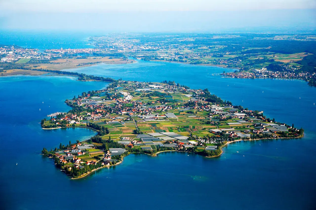 Die Insel Reichenau, ein Juwel im Bodensee, zeigt sich mit ihren Feldern, Gewächshäusern und malerischen Dörfern.