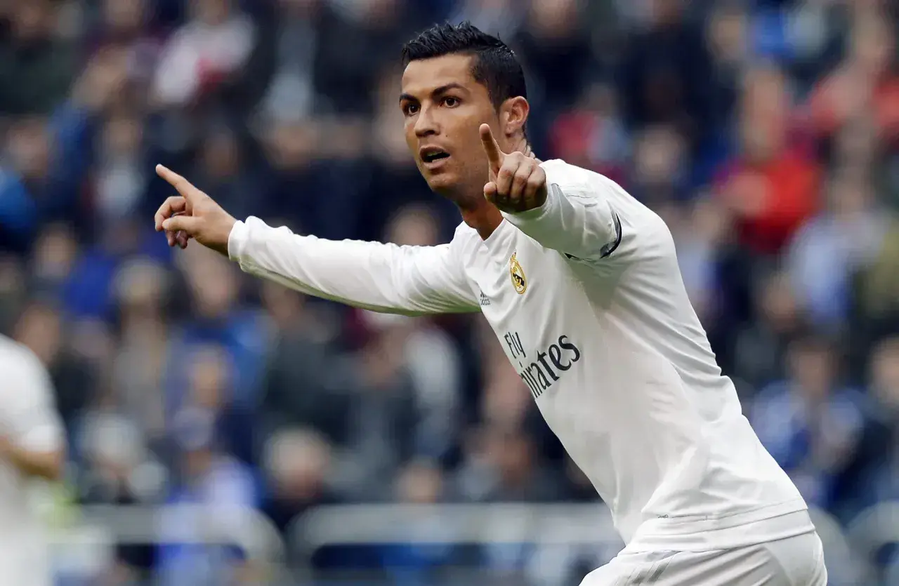 Cristiano Ronaldo w białej koszulce Realu Madryt, z uniesionymi palcami, jakby ogłaszał swój wzrost.