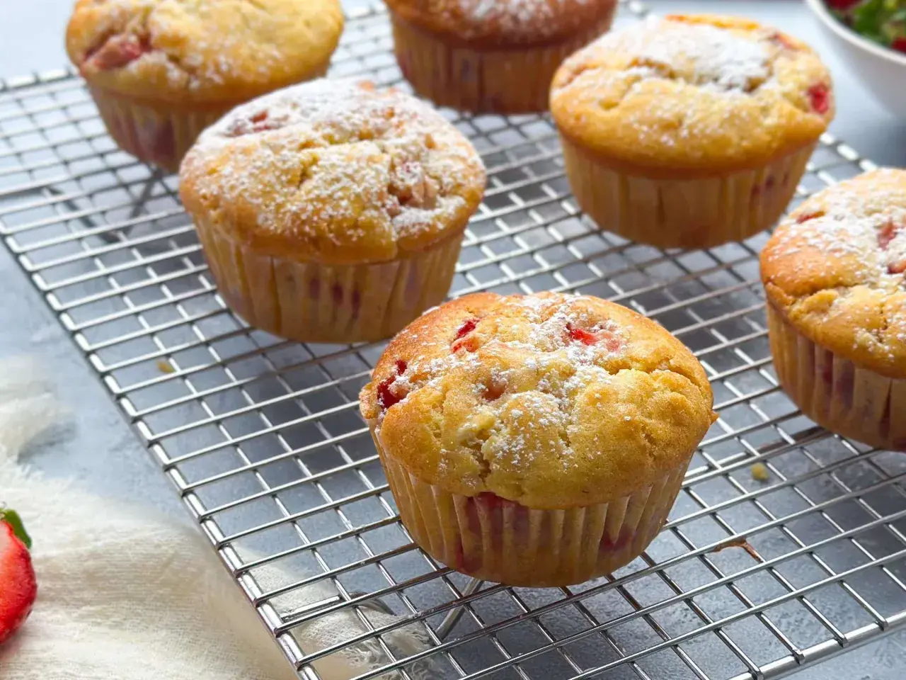 Frisch gebackene erdbeer muffins, mit Puderzucker bestäubt, auf einem Kuchengitter.