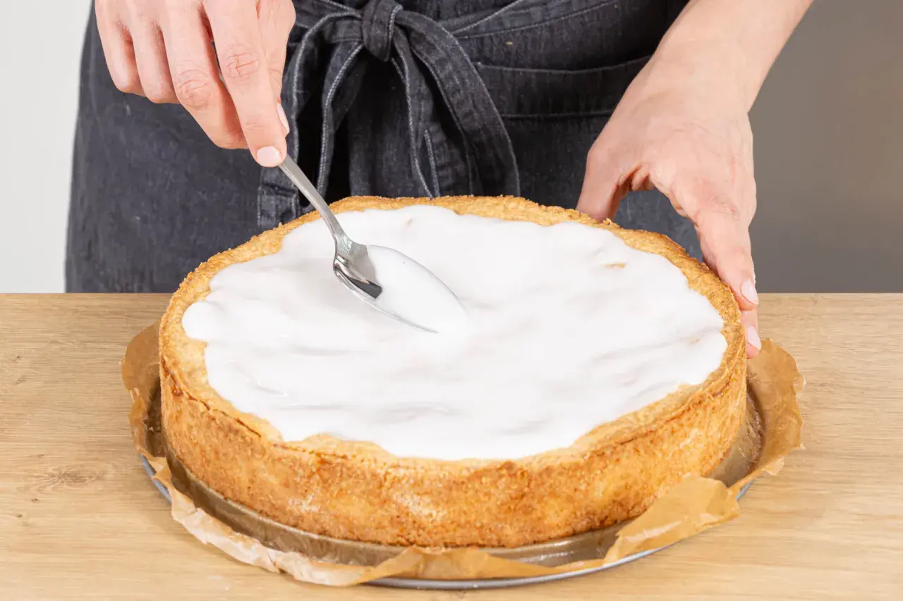 Landfrauen-Rezept: Ein goldbrauner Apfelkuchen wird mit einem Löffel mit süßem Guss überzogen.