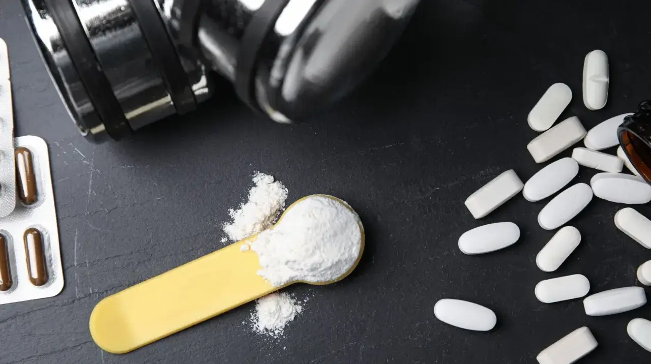 Bilancia, pillole e polvere bianca su un cucchiaio: cosa è meglio, proteine o aminoacidi per aumentare massa?