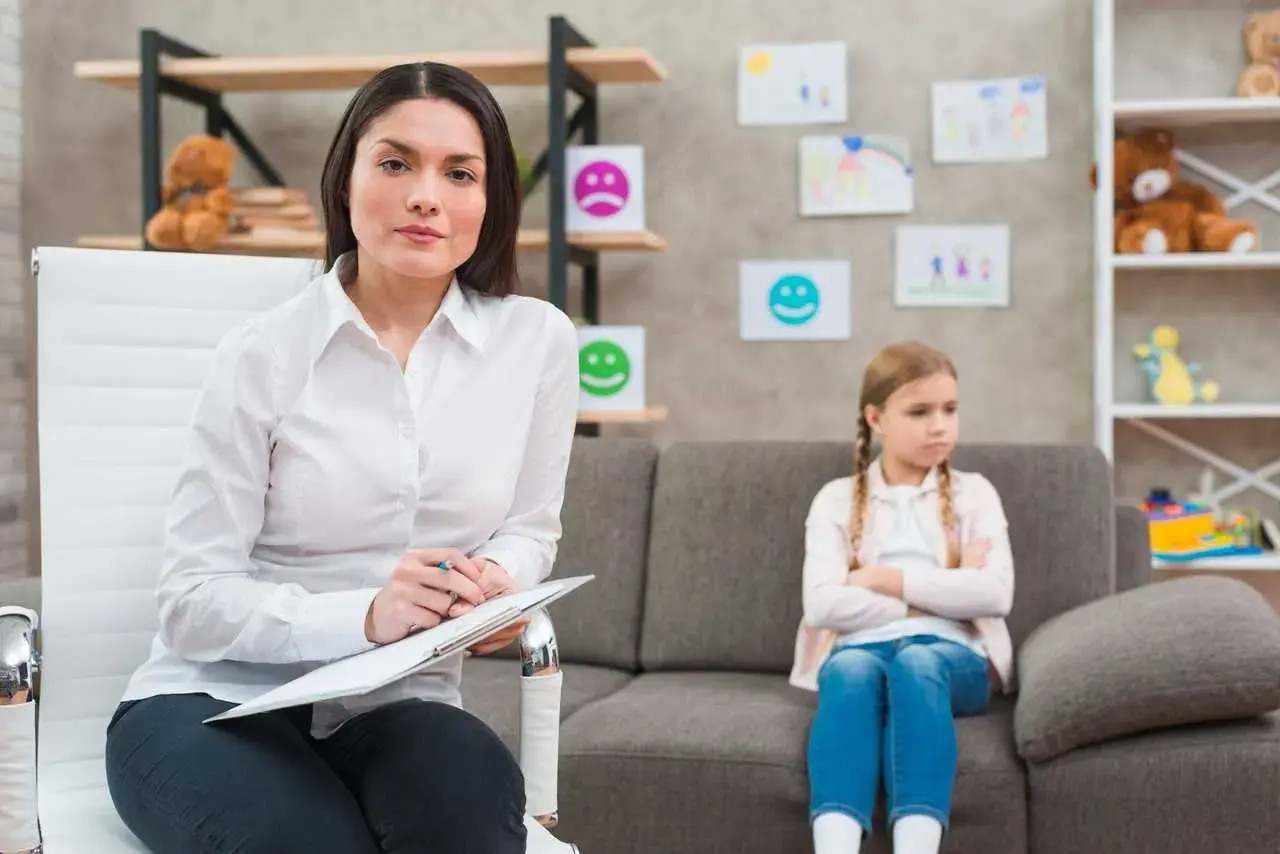 Psycholog z notatkami podczas sesji z dzieckiem. To przykład przygotowania pedagogicznego dla psychologów, wspierającego rozwój emocjonalny najmłodszych.