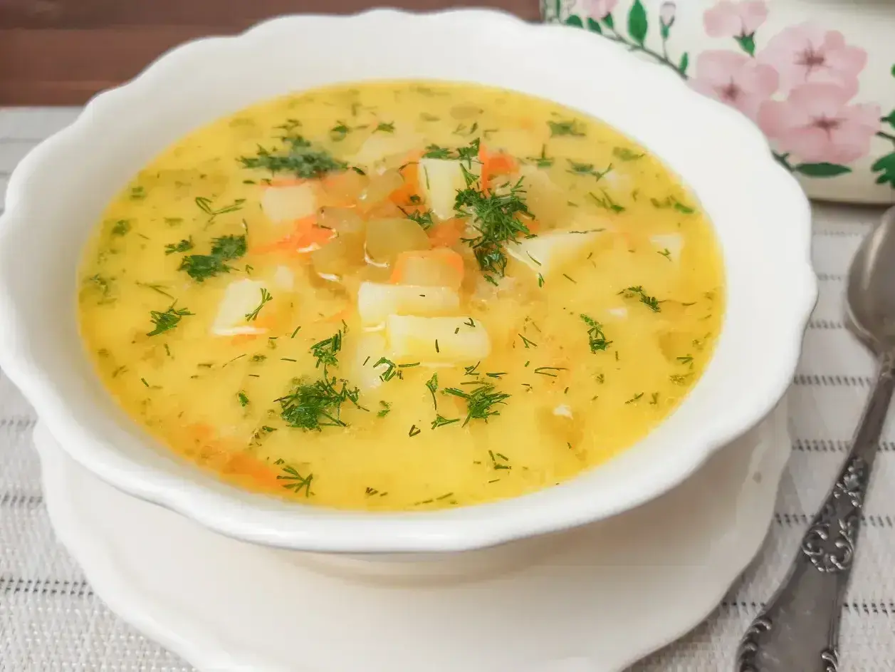 Aromaticzna zupa ogórkowa z ziemniakami i marchewką, posypana świeżym koperkiem. Idealna na chłodne dni.