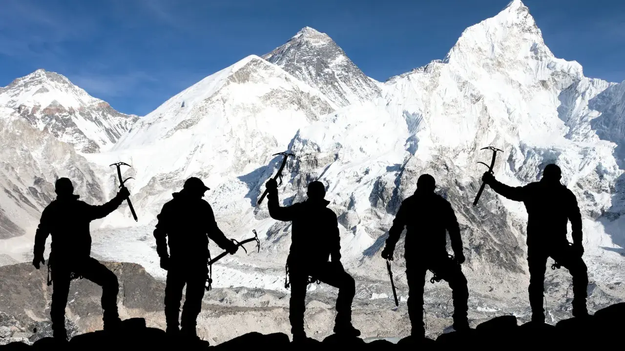Pięciu alpinistów z czekanami na tle ośnieżonego Mount Everestu. To symboliczne przedstawienie, bo ile osób weszło na Mount Everest, to już inna historia.