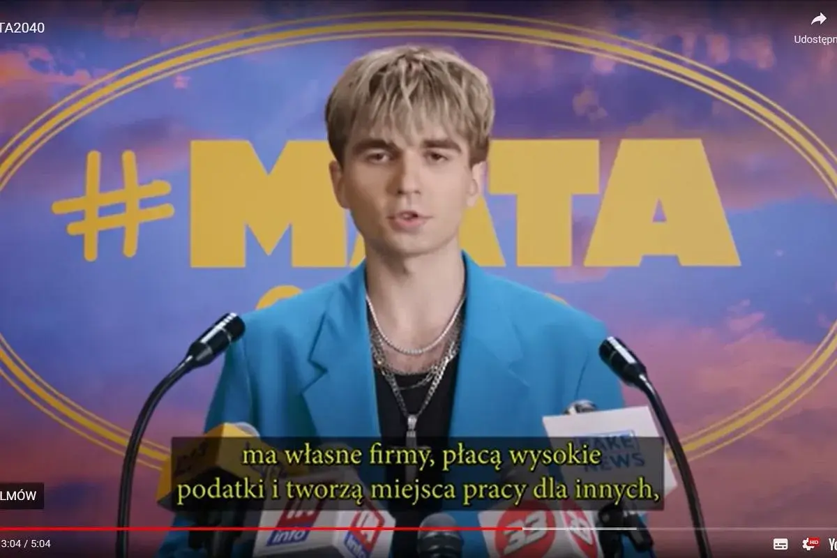 Młody mężczyzna w niebieskiej marynarce, z hasłem #MATA na tle. Mówi o firmach, podatkach i tworzeniu miejsc pracy.