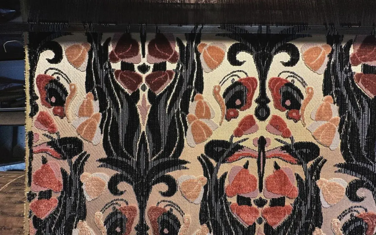 Tessitura Bevilacqua Venezia: un tessuto prezioso con motivi floreali e volute nere su fondo beige, che evoca l'eleganza veneziana.