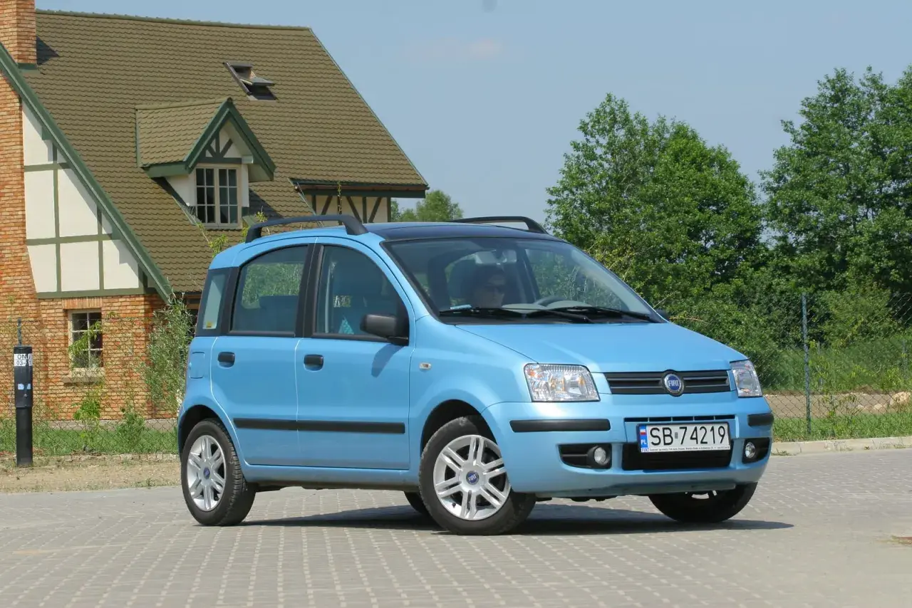 Niebieski Fiat Panda z czarnym dachem i relingami, z widocznymi przednimi żarówkami.