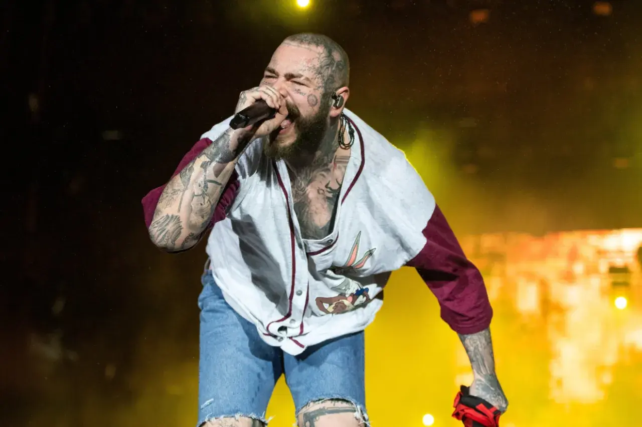 Post Malone Polska na koncercie, śpiewa z pasją w koszulce z Królikiem Bugsem i dżinsowych szortach.