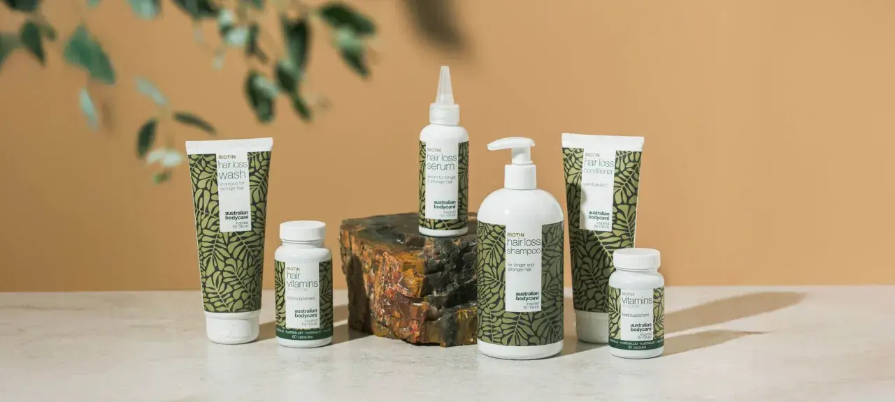 En samling hårvårdsprodukter med biotin, inklusive schampo, balsam, serum och kosttillskott för starkare hår.