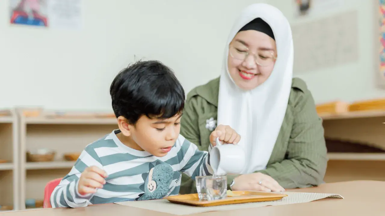 A child practices pouring water in a Montessori classroom, learning practical life skills inspired by nature.