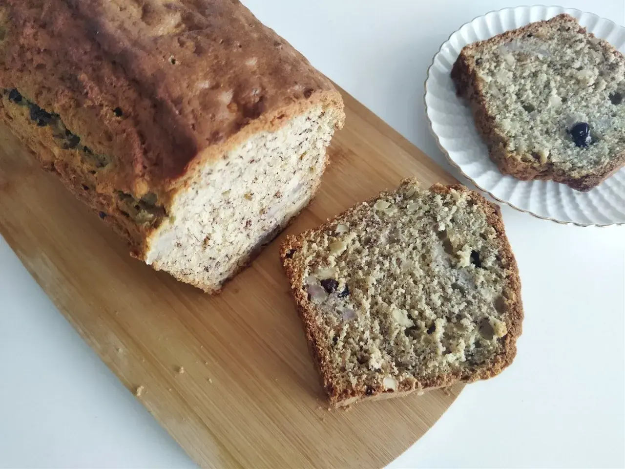 Domowy chlebek bananowy z kawałkami orzechów i rodzynek, pokrojony na desce.