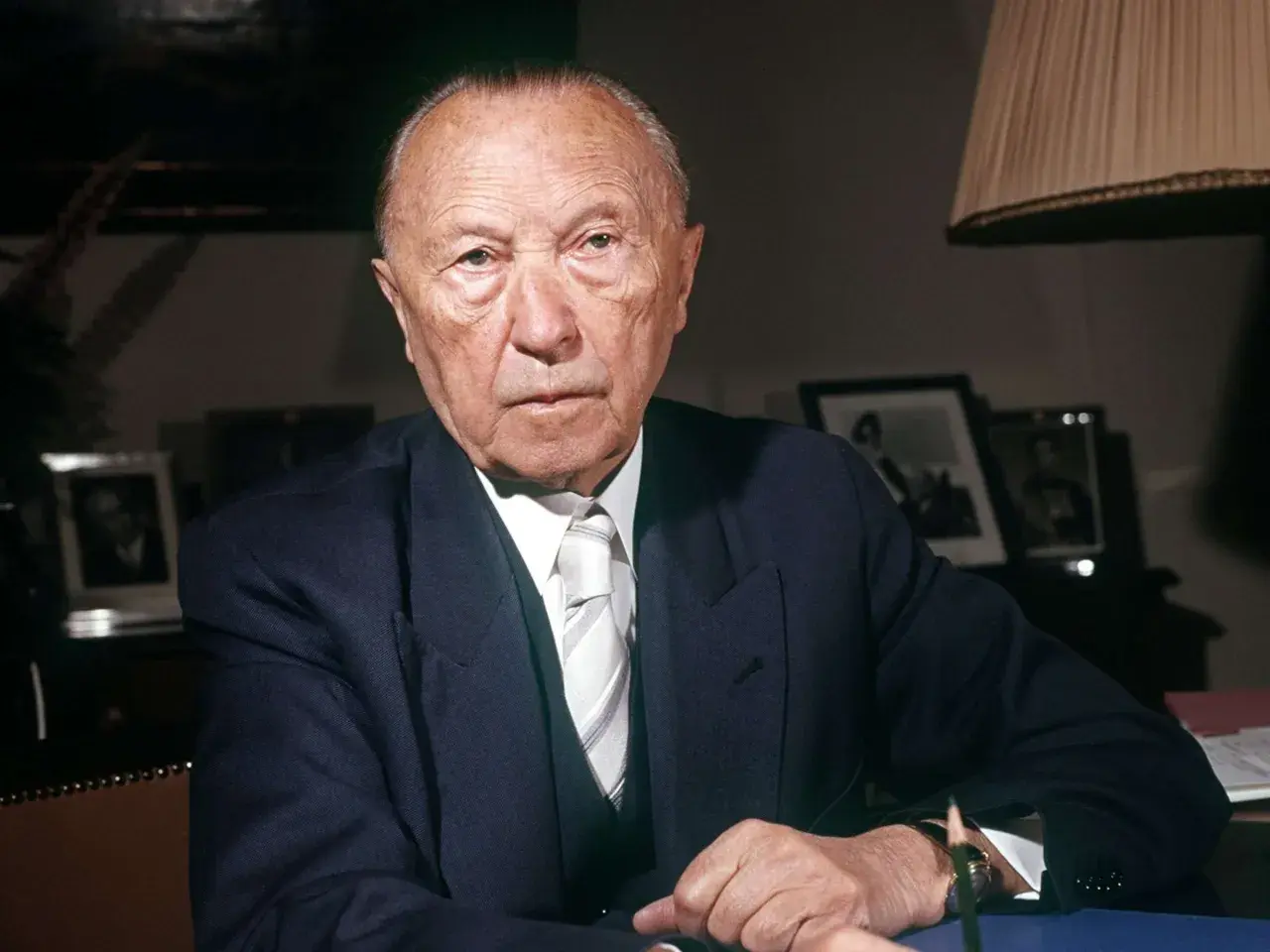 Konrad Adenauer, der von 1949 bis 1963 Bundeskanzler der Bundesrepublik Deutschland war, sitzt im Anzug am Schreibtisch.