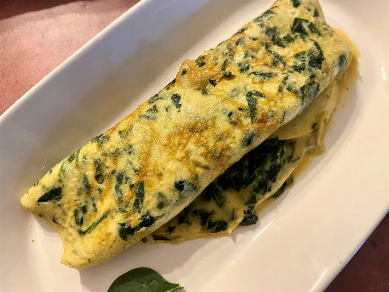 Une omelette aux épinards, dorée et moelleuse, servie sur une assiette blanche. Un délice simple et sain.