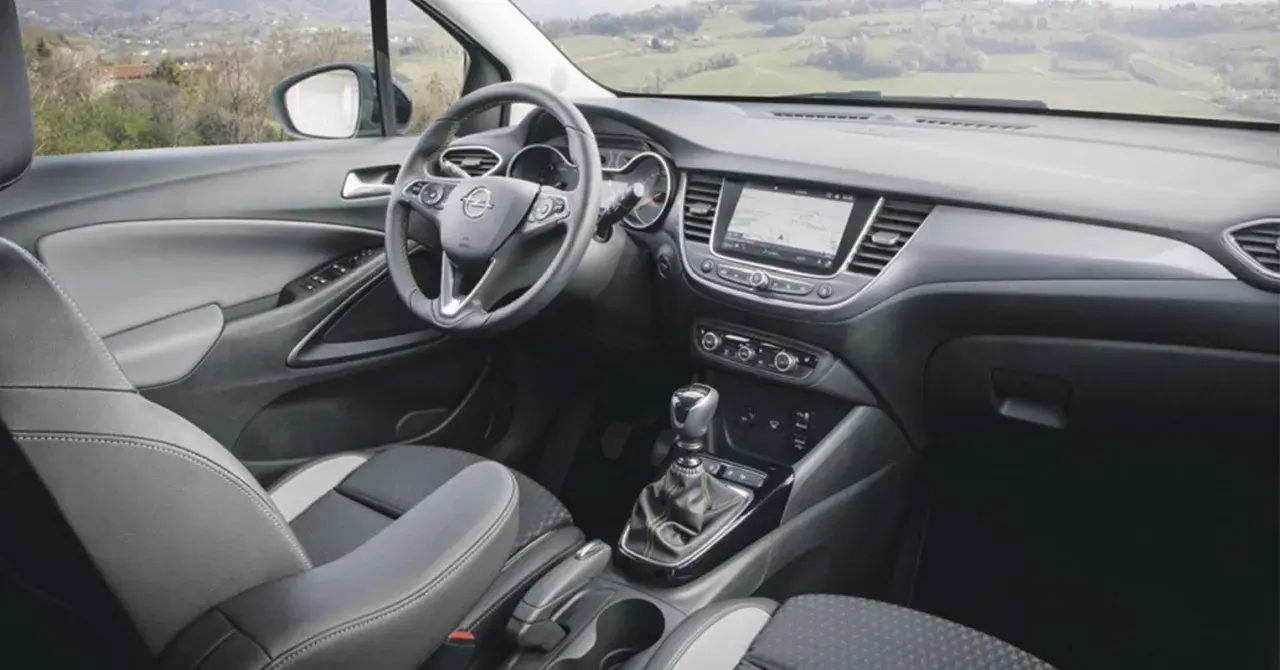 Interior del Opel Crossland X con asientos grises y negros, volante multifunción y pantalla táctil.