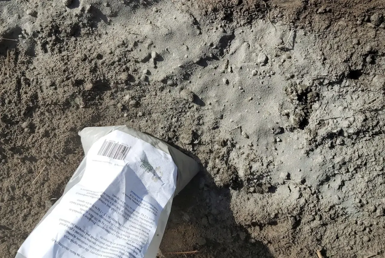 Opakowanie mączki bazaltowej leży na ziemi. Czy mączka bazaltowa jest szkodliwa? To naturalny nawóz, który poprawia strukturę gleby i dostarcza minerałów.