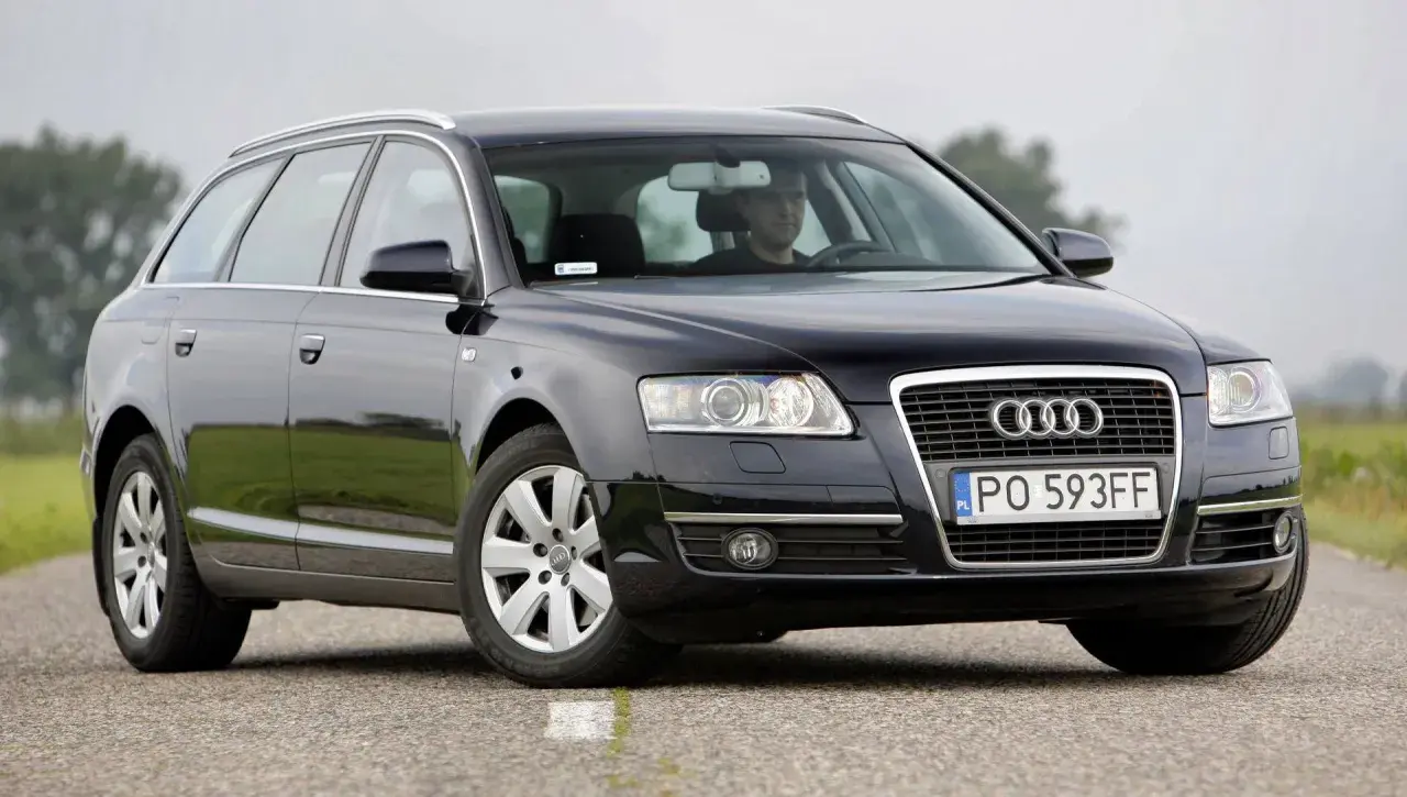 Audi A6 C6 kombi, przygotowanie do wymiany żarówki do jazdy dziennej. Kierowca w kabinie.